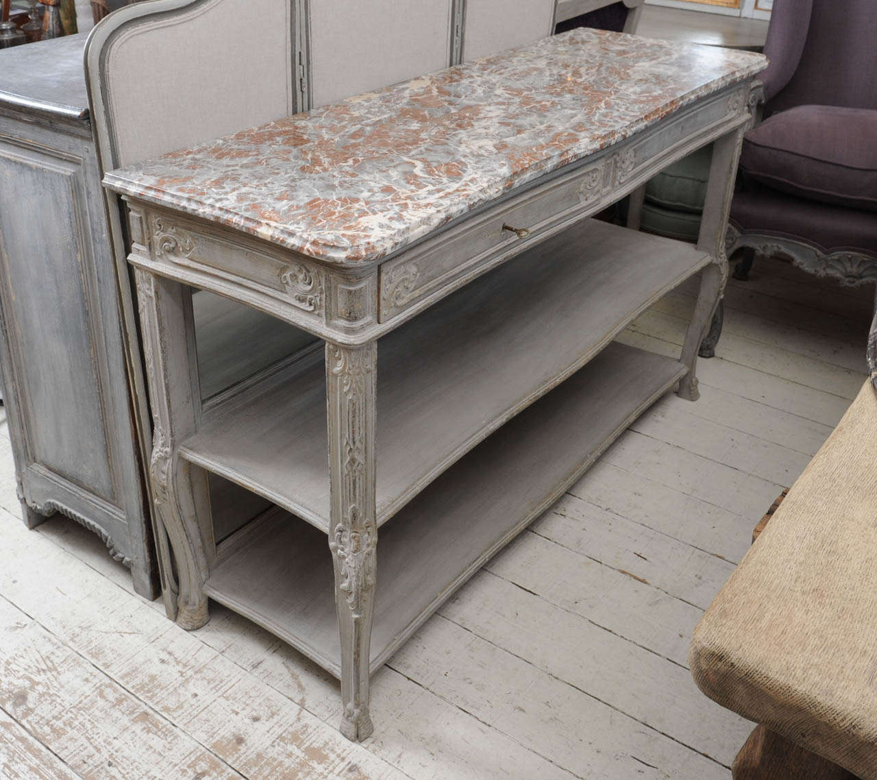 Grey patinated oak buffet with drawers and a marble brown/grey top. On the background a mirror.