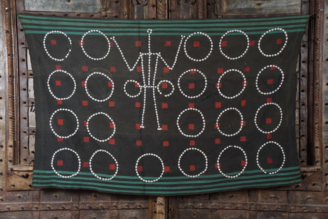 Hand-embroidered Shawl with cowrie shells, a monetary system at the time period. The headhunter at its central image. Wool warp and weft, cowrie shells, and dyed dog hair. Nagaland India.