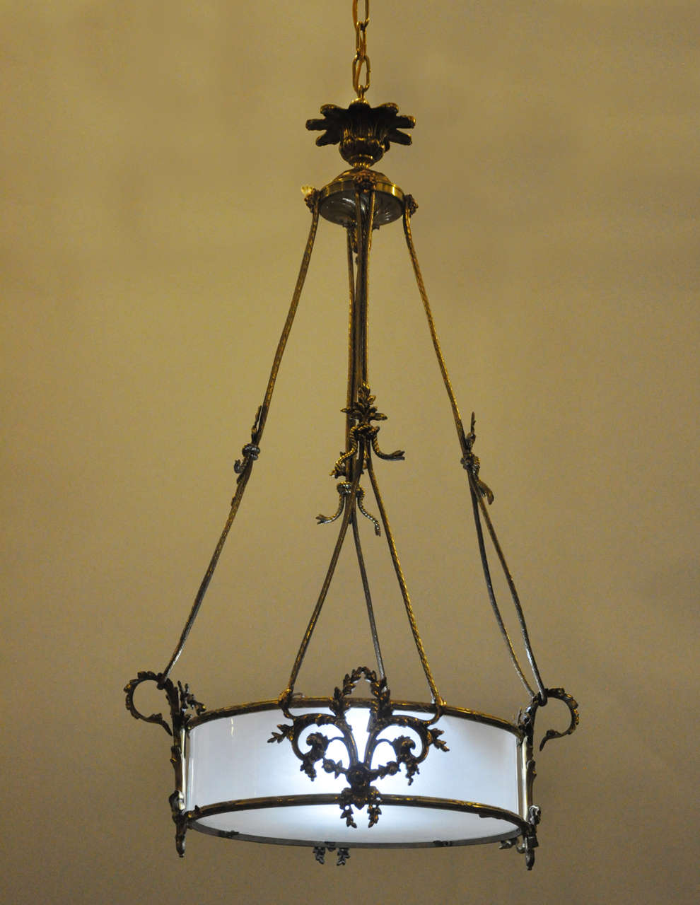 French Louis XVI style bronze and brass pendant chandelier, circular frosted glass shade adorned with bronze neoclassical motifs, supported by brass and bronze suspending supports terminating in a ceiling plate.

Neoclassical design was inspired by