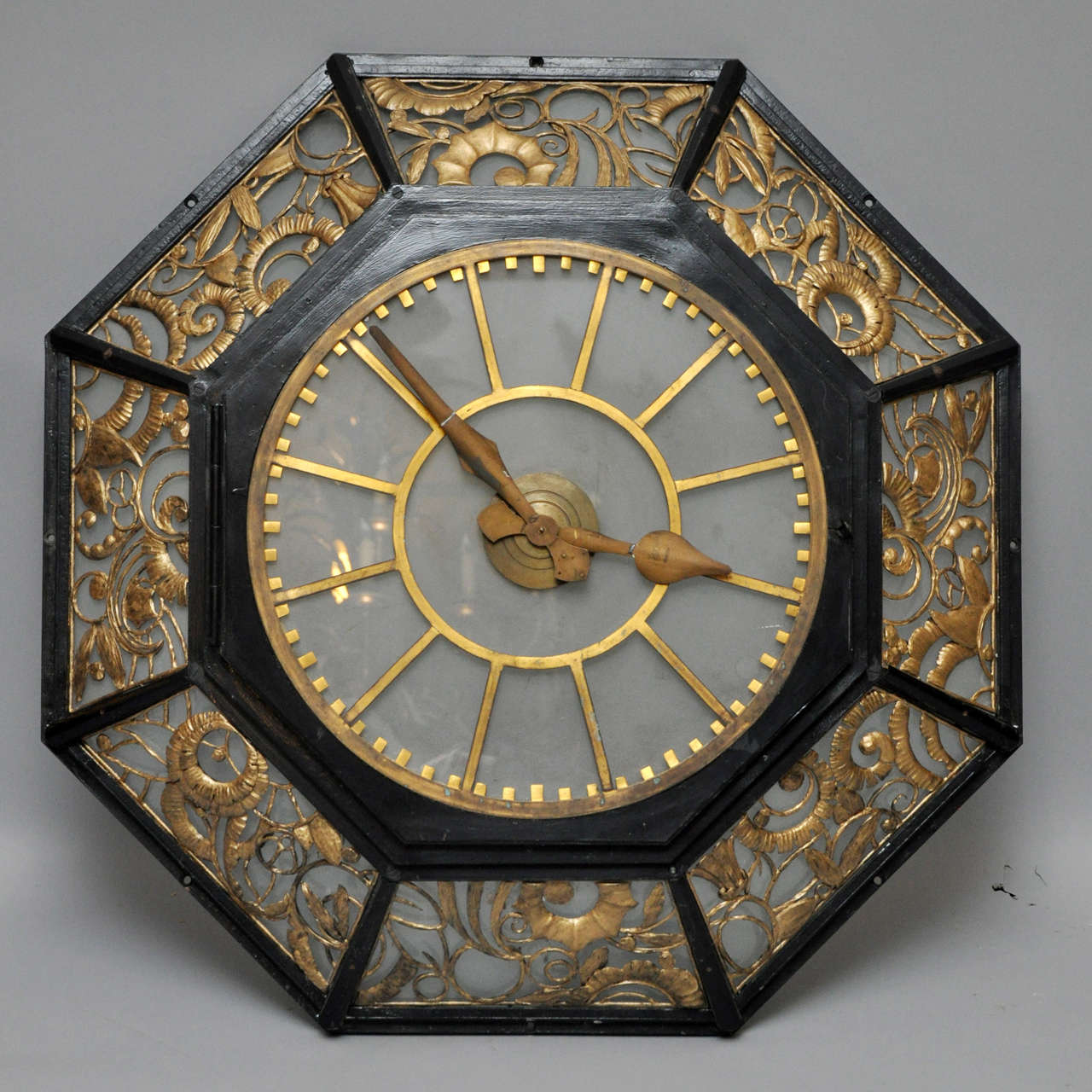 Rare French Art Deco hotel octagon wall clock. Frosted glass dial with bronze markers and painted metal hands, hinged door opens to reveal electric movement. Surrounding octagon shaped outer frame with gilded hand-forged filigree design.