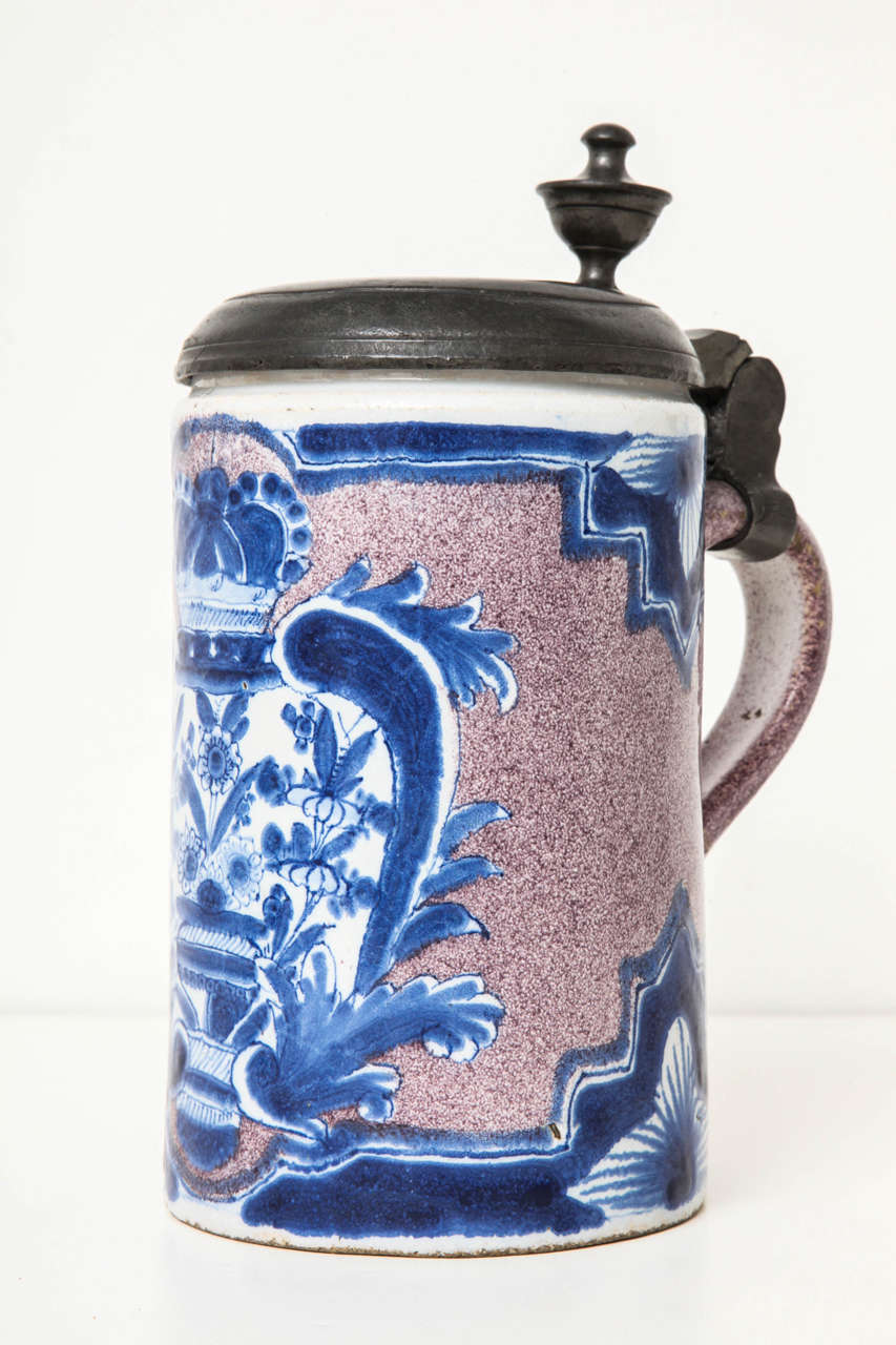 An 18th century German blue and manganese Faience tankard decorated with a crowned basket of flowers with pewter cover marked on the underside 
