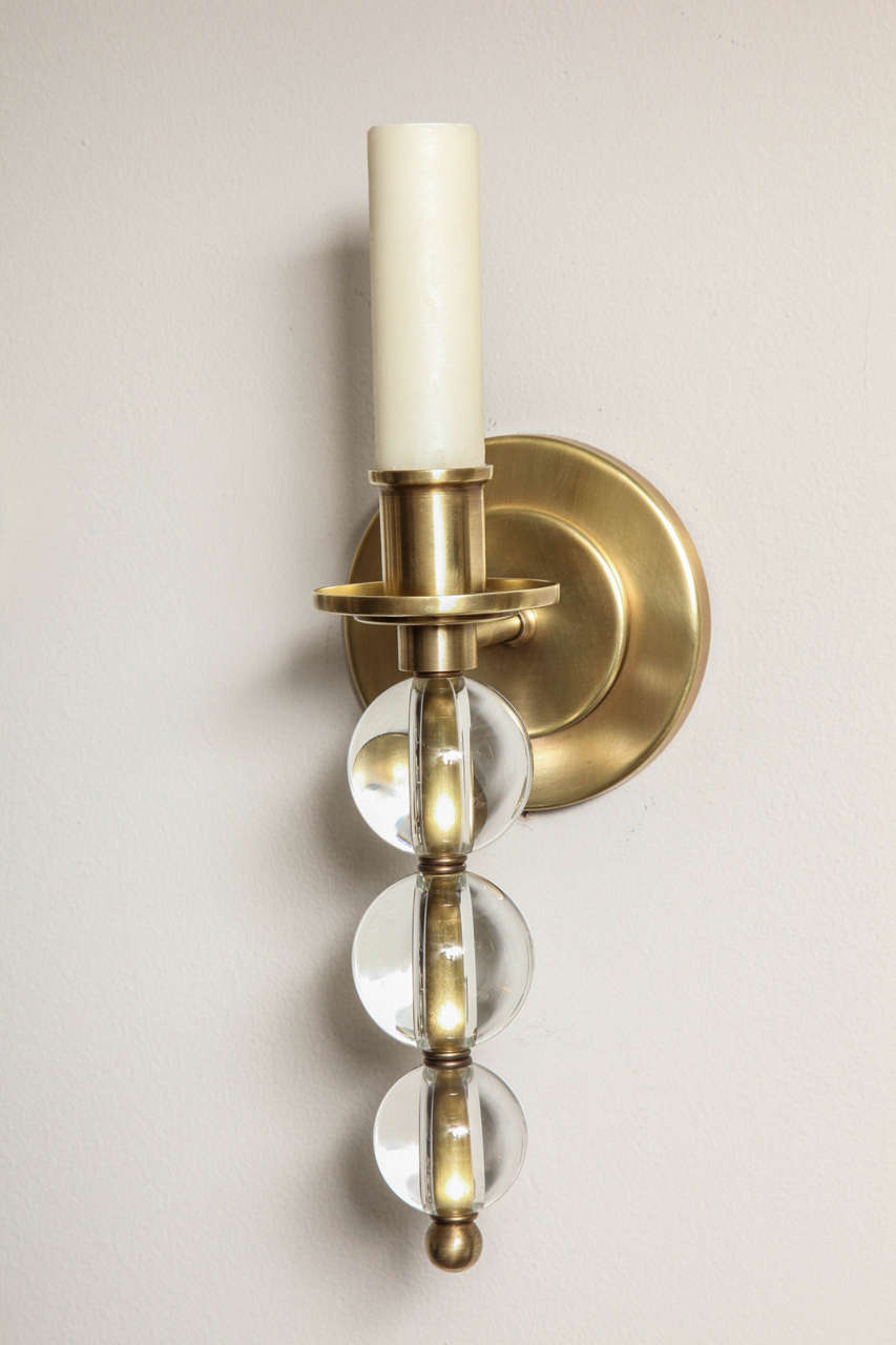 A pair of contemporary design, custom made sconces with glass balls. The round back plate issues an arm with a vertical stem, featuring three glass balls graduating in size. Available in custom sizes and finishes. Sold as a pair can also be