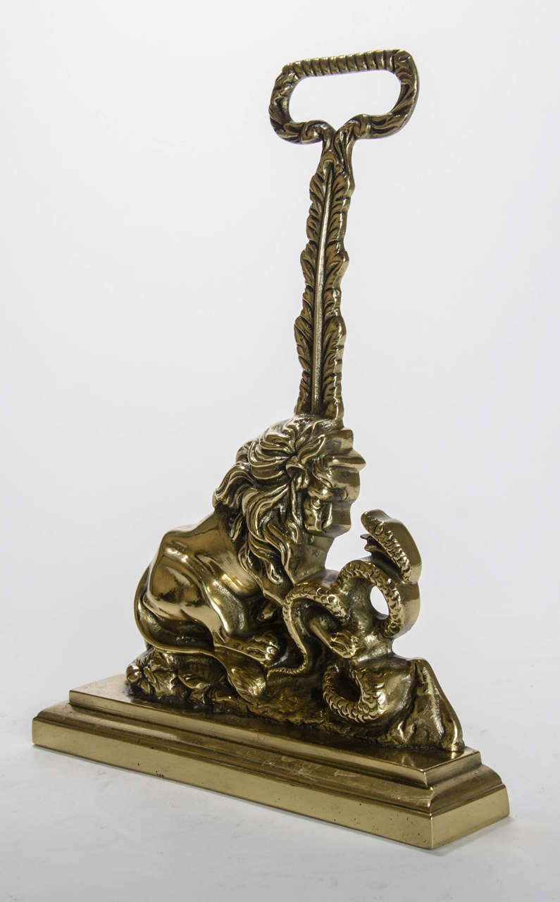 An early nineteenth century door stop cast in the form of a lion attacking a serpent with an acanthus handle and rope twist ring.