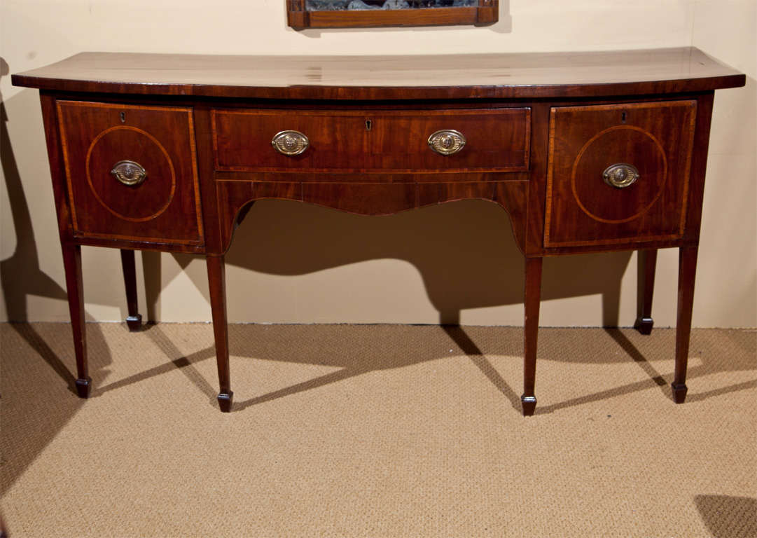 An original George III mahogany bow front sideboard with cross banding and deep drawers on either side.