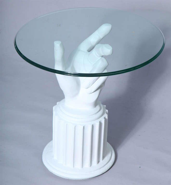 Well-formed plaster hand raised on round fluted base.  Shown with a round glass top.

Once shipped, its top must be affixed to base in order to hold it in place.