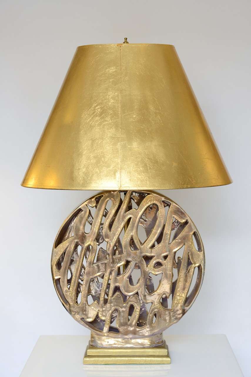 Grande lampe glamour en céramique dorée sur base de bois doré avec abat-jour original en papier doré.