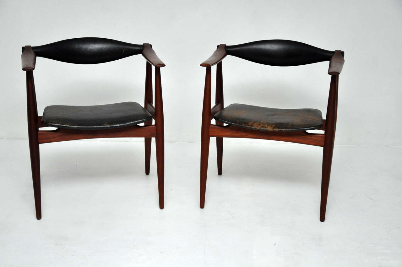 Pair of CH-34 armchairs designed by Hans Wegner for Carl Hansen. Teak frames with original leather. One chair has splits in leather seat.