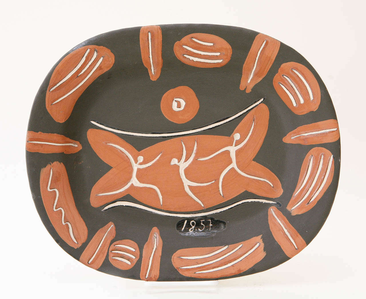 One of an edition of 400 produced, this partially glazed white earthenware clay platter by Pablo Picasso features a trio of dancers in the center and is painted in red, white and black. The front of the platter is also dated 1.8.57. Marked with the