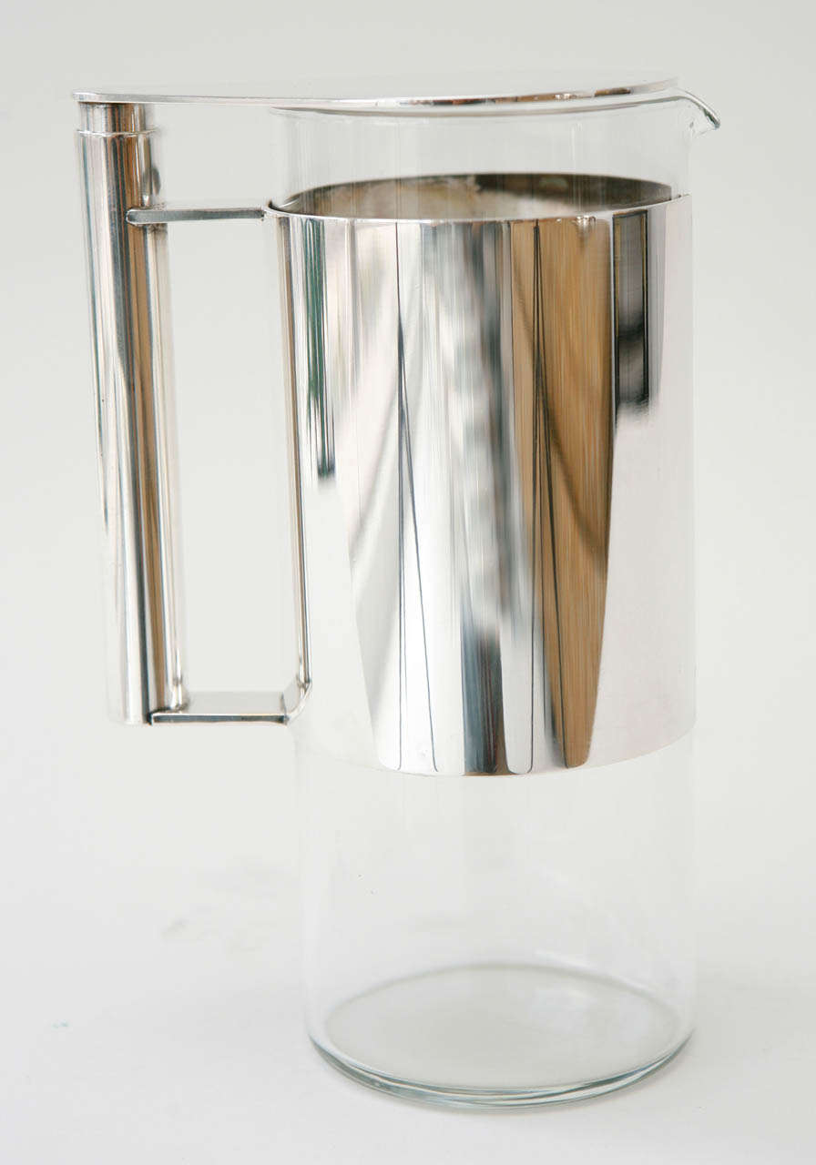 A stylish glass and silver plate pitcher by Lino Sabattini with a swiveling cover at the top of the pitcher. Marked with the Sabattini name and logo on the underside of the handle (see Image 10).