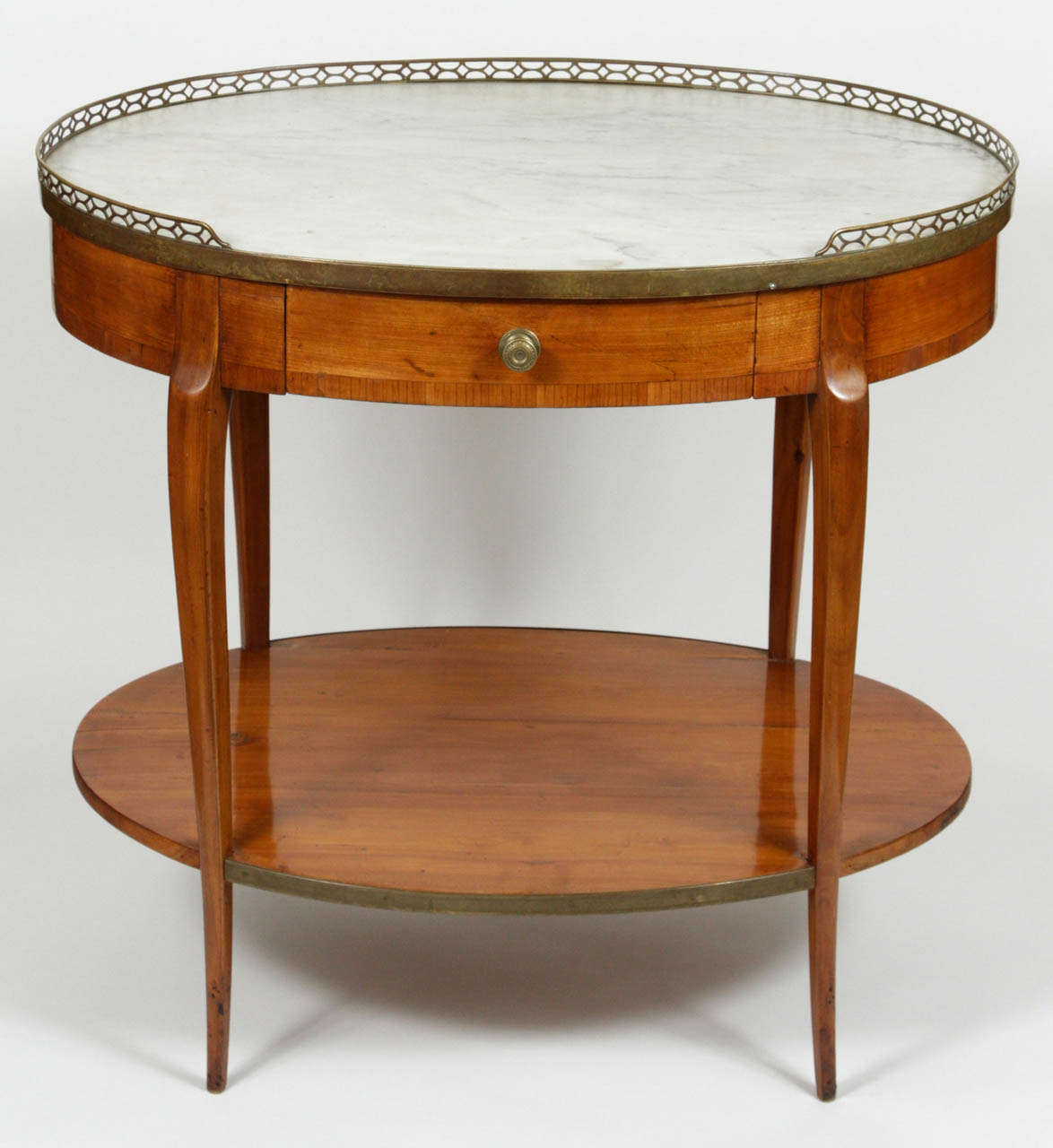 Two-tiered oval Bouillotte table.  Features apron drawer and marble top.  Pierced brass gallery and decorative sabots. French c. 19th century.  

DIMENSIONS: 31