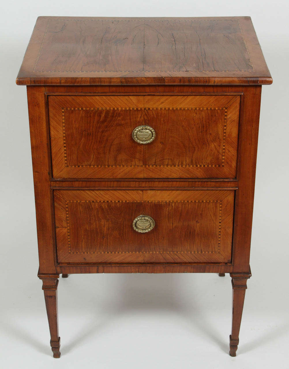 Italian chest with two drawers and square tapered legs terminating in spade style feet. Delicate contrasting marquetry inlay with cross banding details. Original hardware.