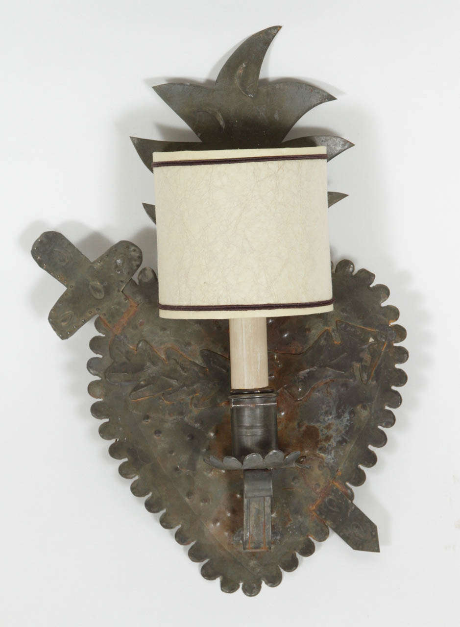 Hammered metal sconce with heart, flame and sword detail. Patina naturally acquitted over time. Slight variations in finish on each item. Clip-on half shade not included.