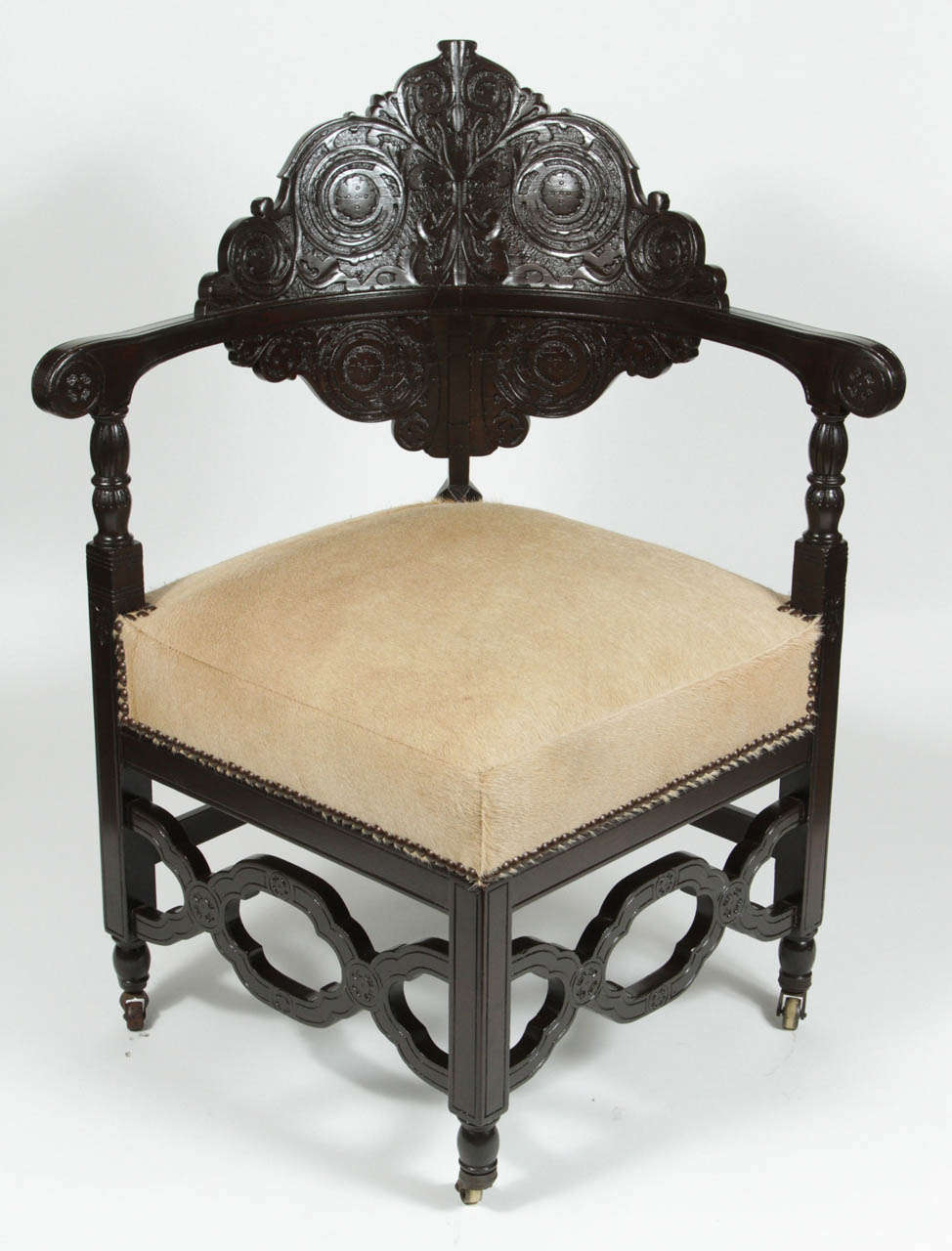 Antique corner chair with carved back on casters. Newly refinished and upholstered in hair on hide with nail heads.