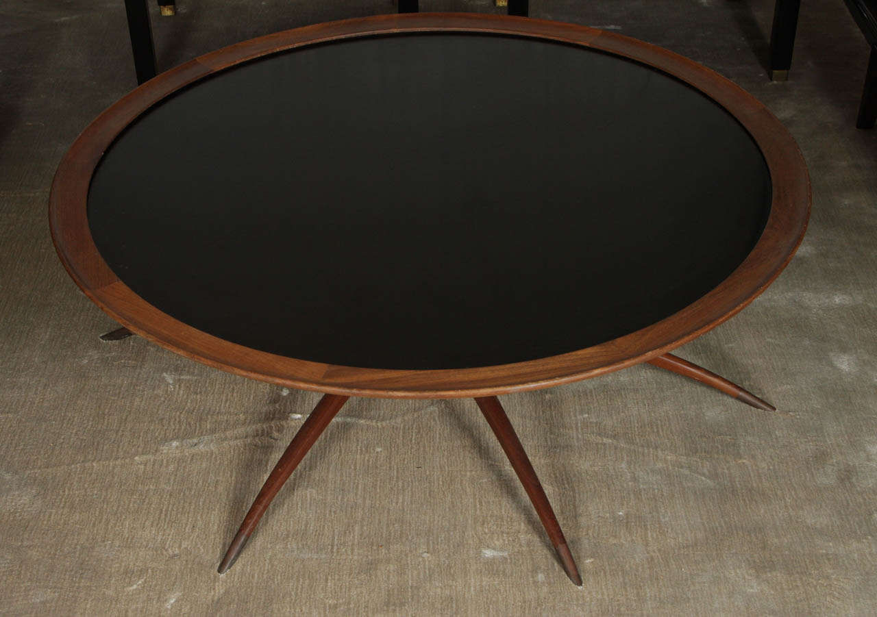 Early 1960's sculptured teak arachnid table with black colored glass top. This six legged table is an extremely well crafted design with classic lines and an elegant presence. Each leg is adorned with a tapering brass sabot. The inset brass piano