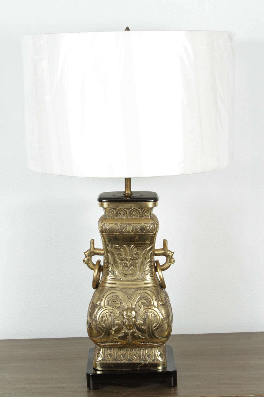 Pair of Asian motif aged bronze table lamps with wood fittings in the style of James Mont. Rewired with brass fittings in a bronze finish, full range dimmer socket and French style rayon covered cords.