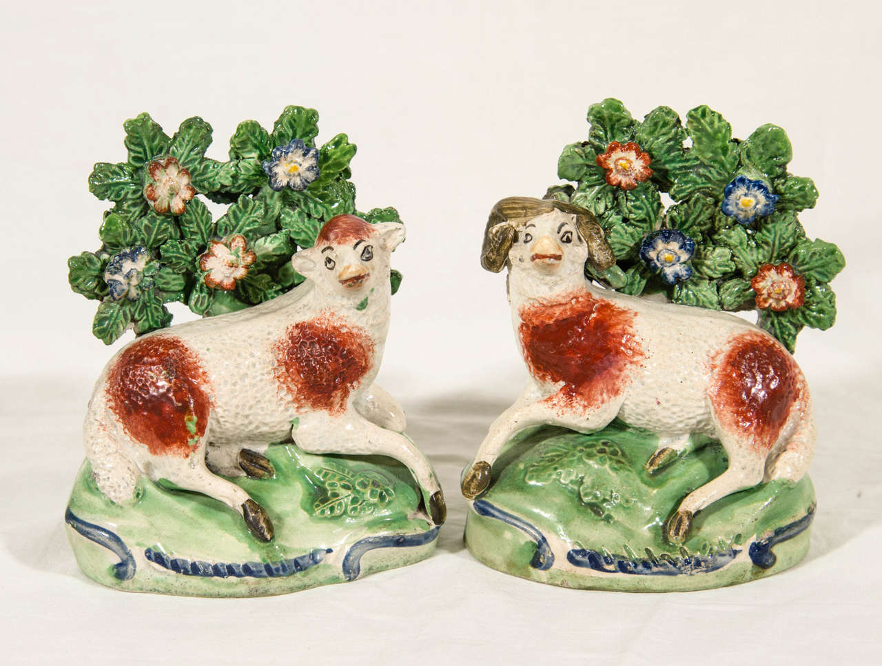 A charming and decorative pair of early Staffordshire pottery figures of a ram and ewe. They are a true pair modeled resting on 