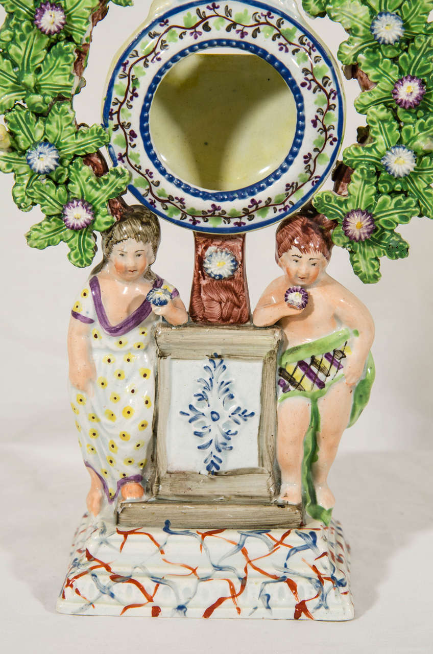A wonderful Staffordshire pottery watch holder flanked by two children. Above them bocage decoration with three small birds among the leaves. 
The piece has excellent enameling. The colors are bright. The attention to detail superb.