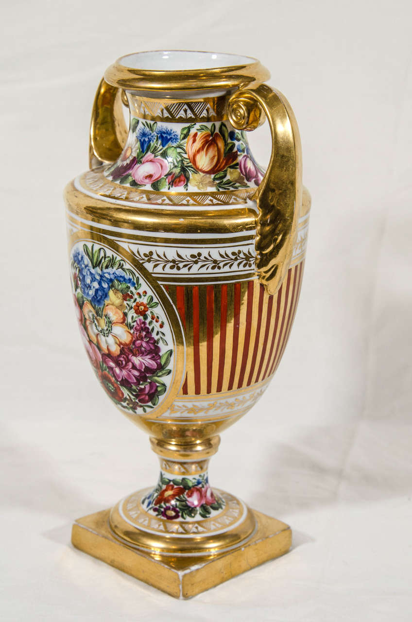 A lovely mantle vase painted in the style of Thomas Baxter with red and gilt stripes around beautiful bouquets of flowers.