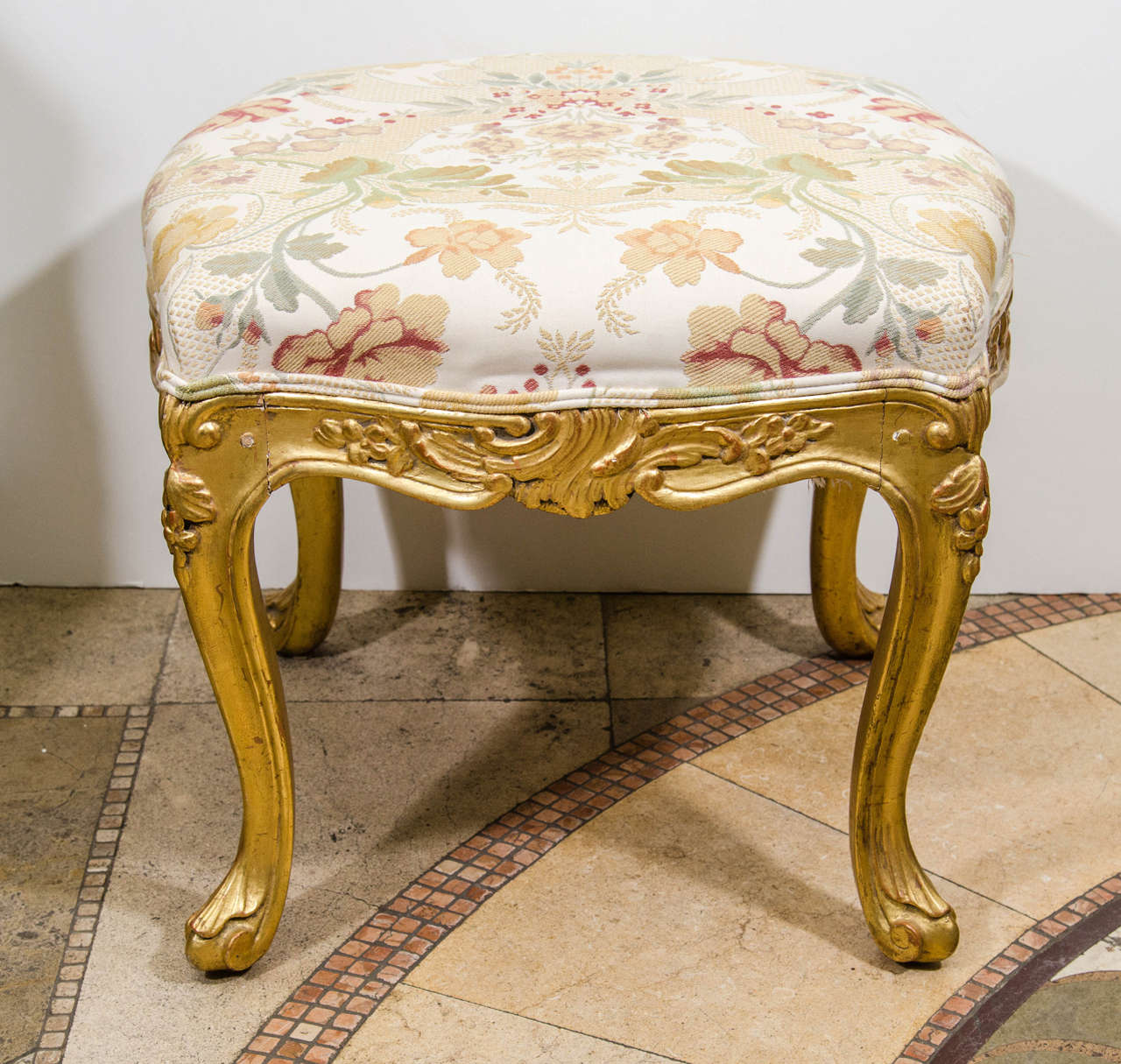 A pair of Louis XV style carved giltwood upholstered square stools with serpentine folate caved apron and cabriole legs.