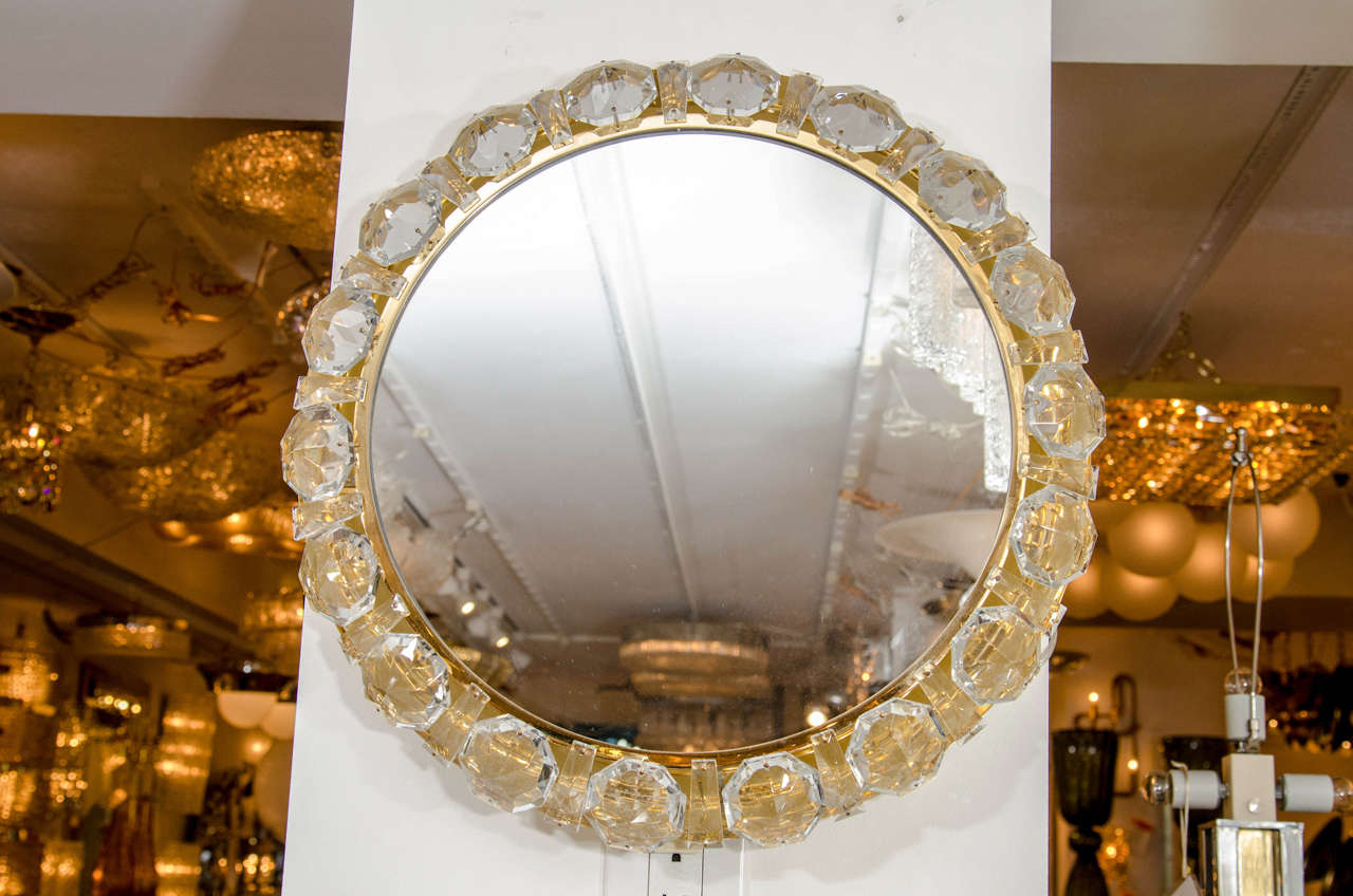 Round brass mirror featuring a surround composed of facet cut crystal strips and 