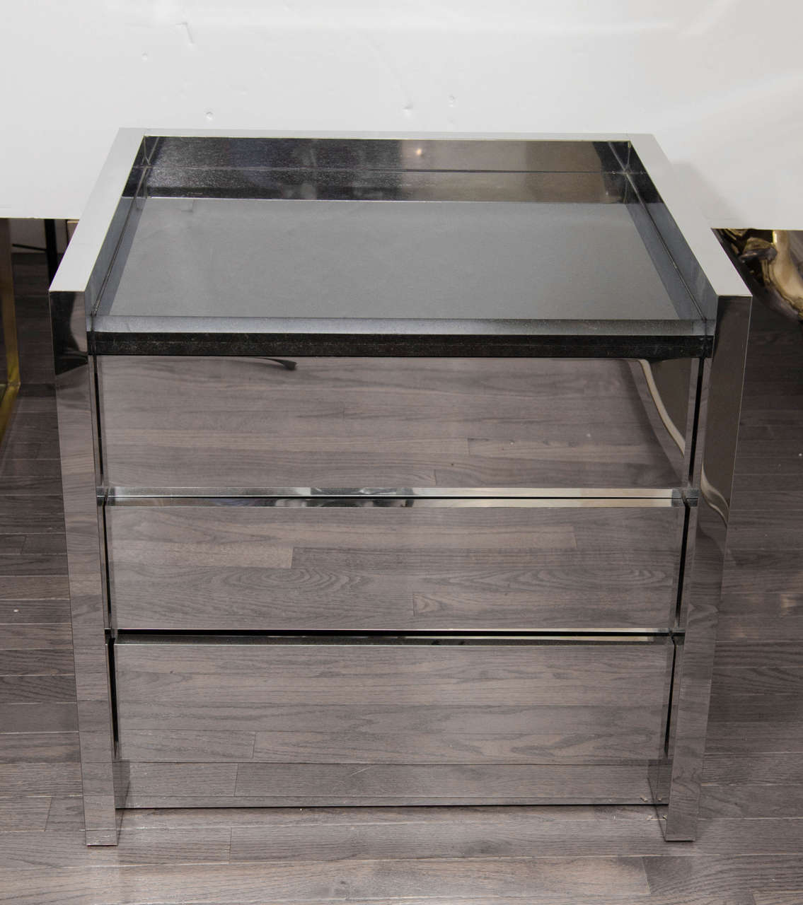 Polished stainless steel chest of drawers with granite top.