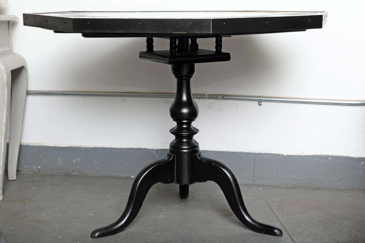 The classical Regency card table received a twist with black semigloss refinished bottom. The original octagonal mirrored hand painted top makes this piece a Hollywood Regency card table with lots of glamour...