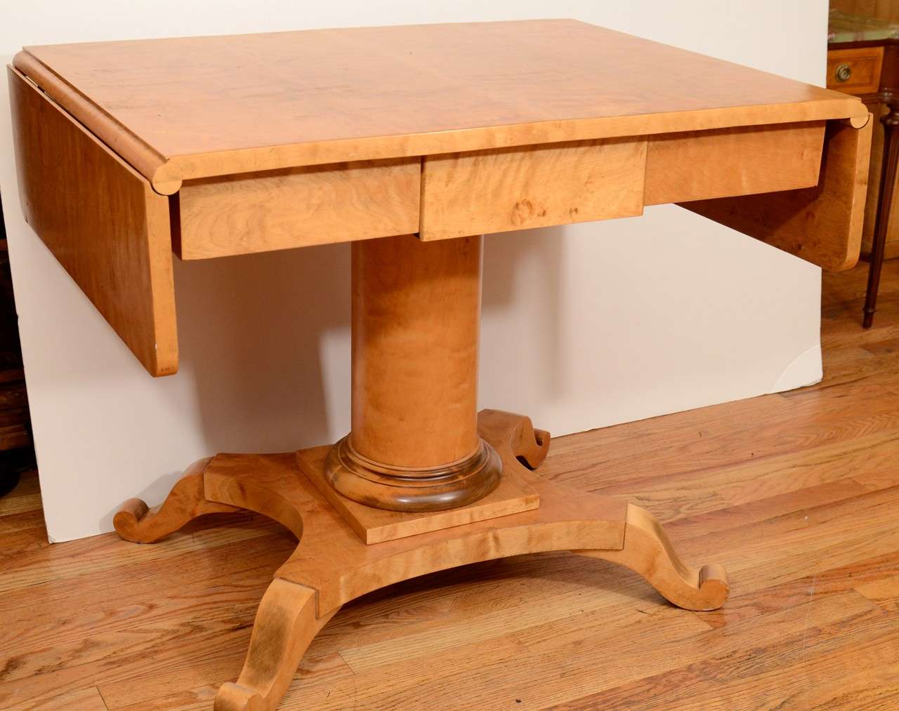 A birch, pedestal table, normally positioned prominently between sofa and armchairs, for the comfortable imbibing of various beverages or a light meal. Modern usages noted are petite dining table with the dropped leaves raised, or desk, as the apron