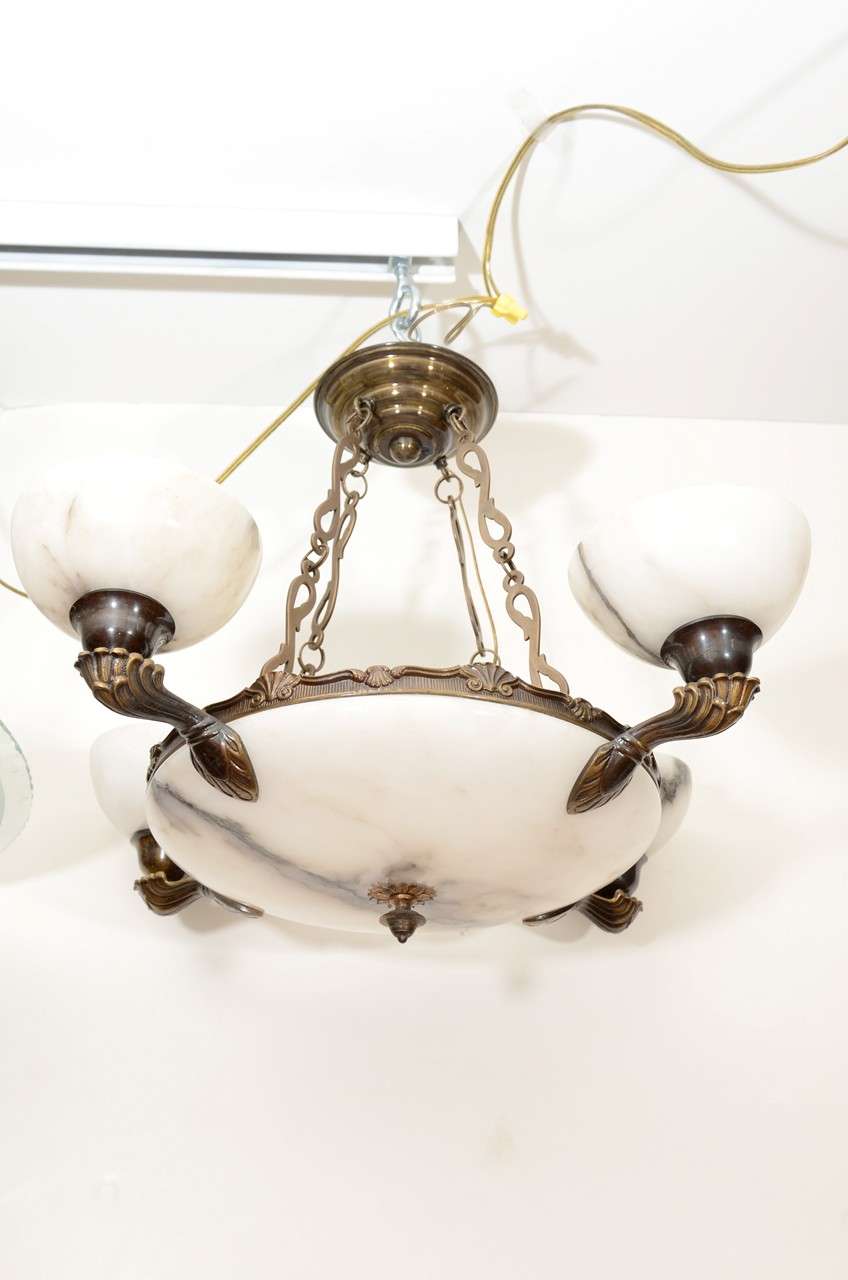 A symmetrical design, featuring a bronze-rimmed, white, veined alabaster bowl, with four bronze arms and matching alabaster cups. Each cup holds one 25 watt bulb; the bowl holds a 40 watt bulb.

Custom rewiring to your specified drop is included