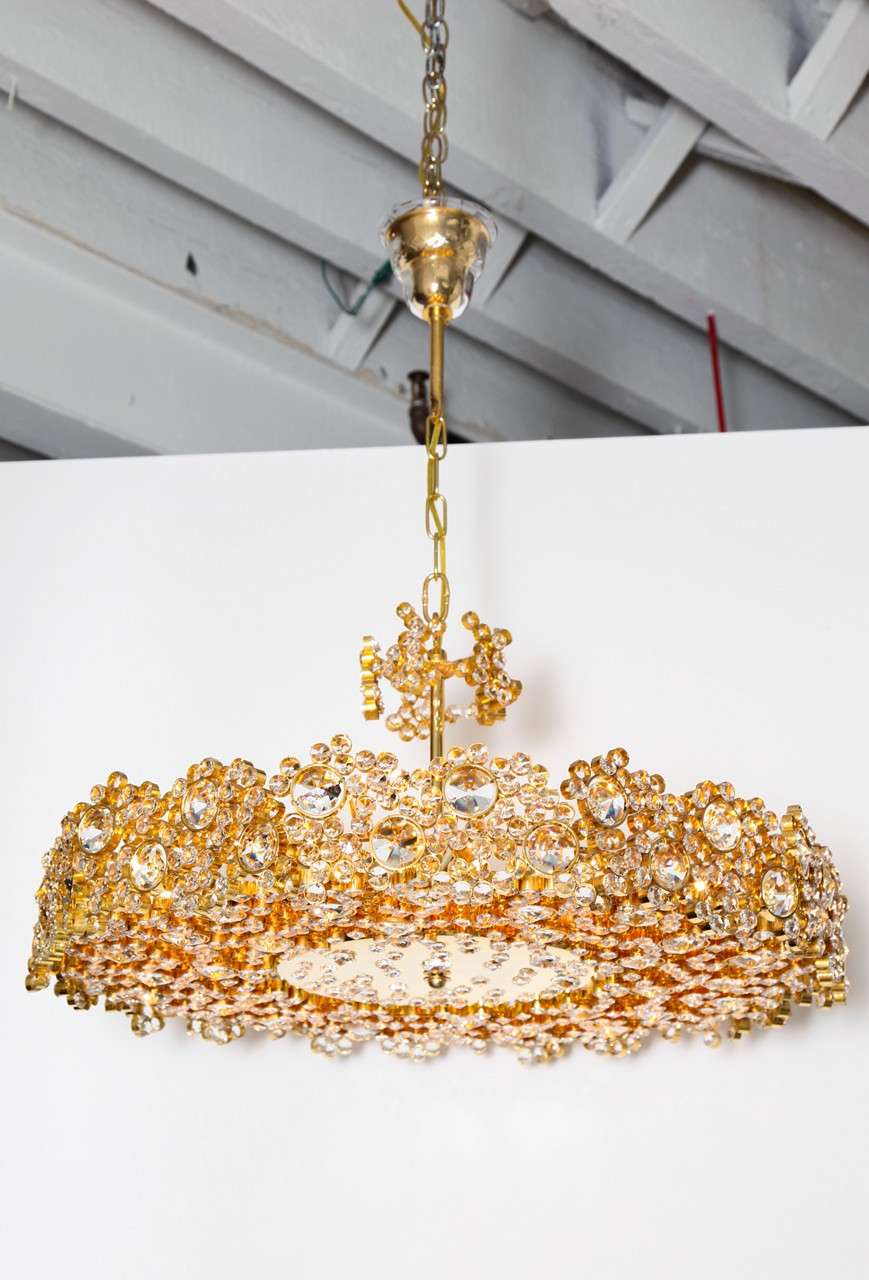 Spectacular jewel-like midcentury chandelier with hundreds of crystals set in gold plated brass, Austria, circa 1960. The chandelier has an original crystal canopy and is newly electrified with 15 candelabra sockets.