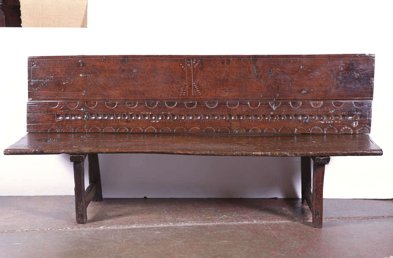 Beautiful antique fruitwood bench from the Pyrenees of Spain; crafted, circa 1740, the rustic bench made with single chestnut planks, features hand-carved geometric designs on the back and two sets of square legs connected with a stretcher. This