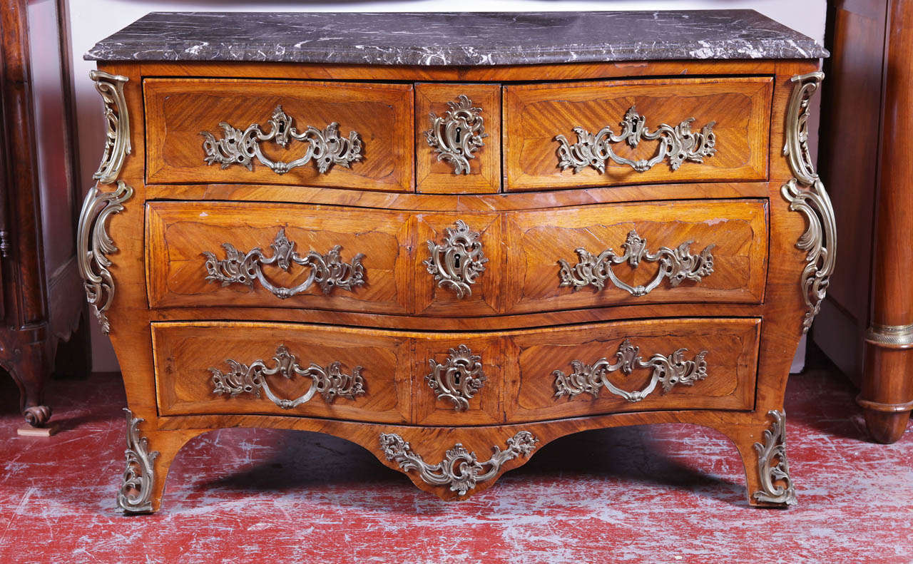 Elegant early 19th century Regence bombe commode with grey marble top and marquetry. Beautiful ormulu bronze decorations, this chest features 3 drawers across the front and 2 large drawers underneath.