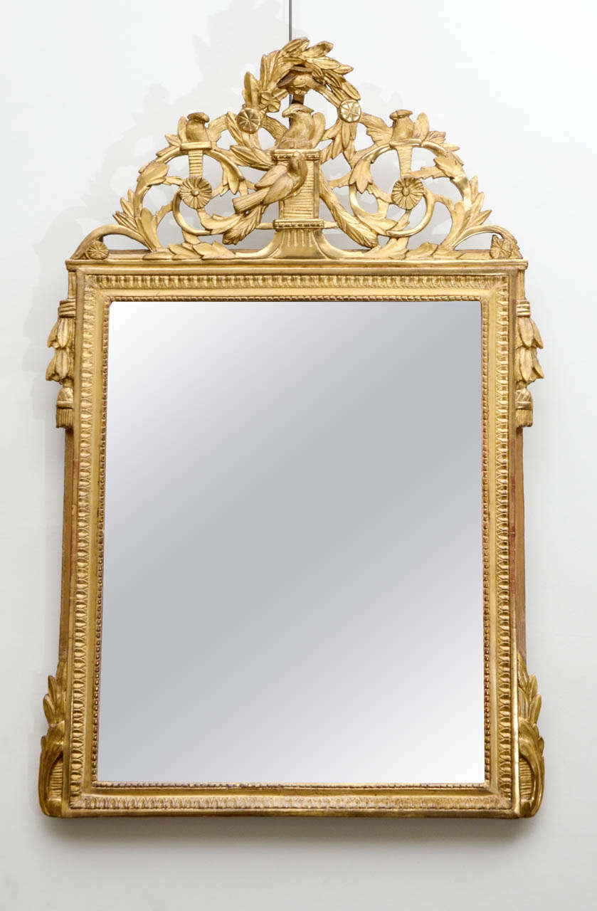 Carved and fine gold gilded mirror. Pearls, waterleaves, foliage and vines scrolls decor. Carved pediment. Original gilding and mirror.
