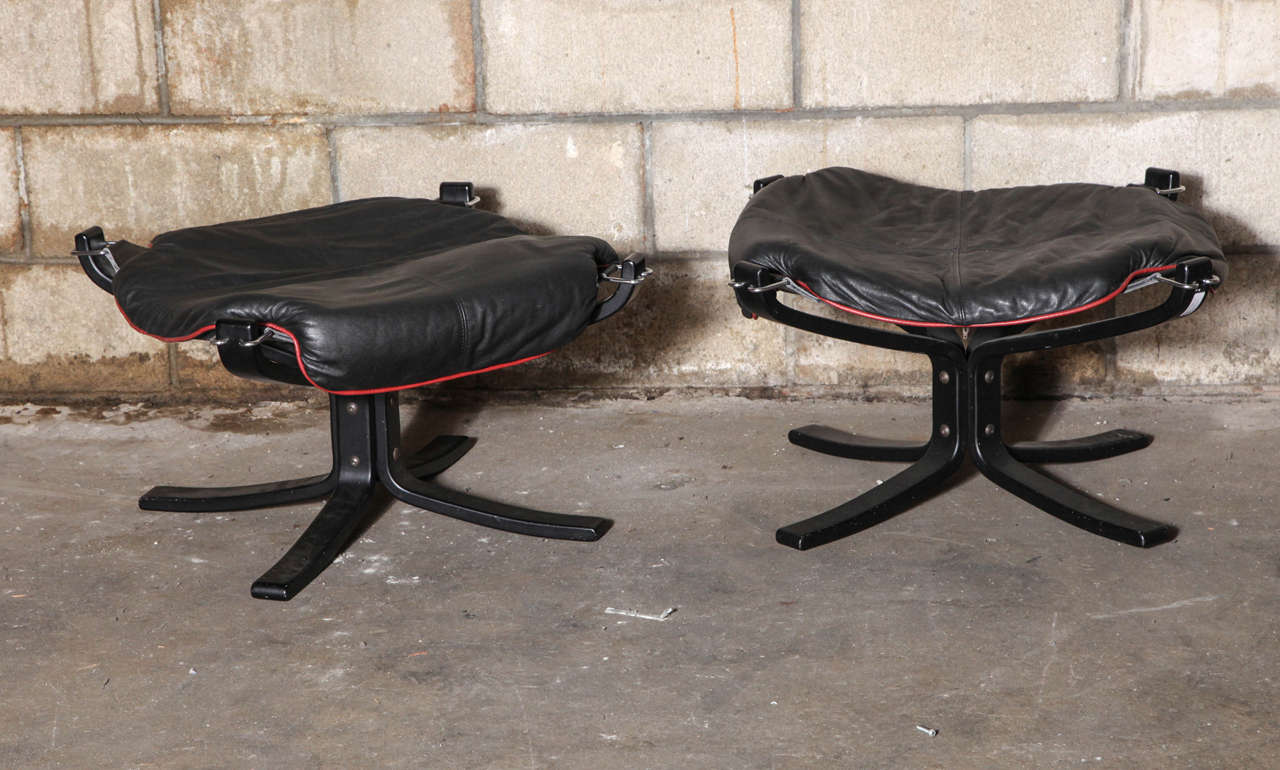 Iconic sling-shaped ottomans with ebonized bentwood bases. Original leather upholstery in black with red piping. Signed with Vatne sticker to frame.