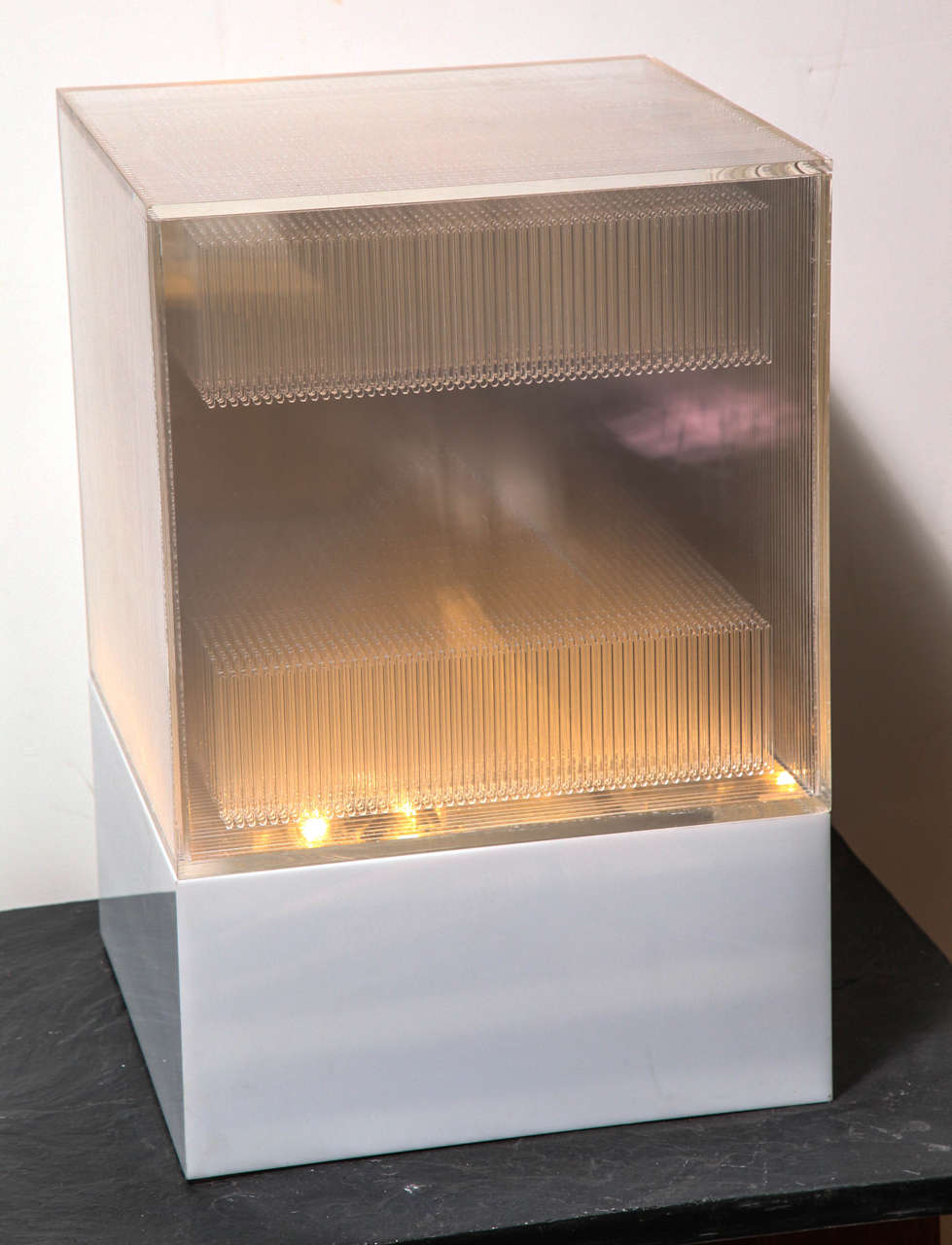Neal Small Optical Art Table Top Light Sculpture. Featuring a squared White Lucite base, clear rectangular top with enclosed transparent Lucite panel pyramid design. Dynamic with or without illumination. Handcrafted. Architectural. Sculptural.
