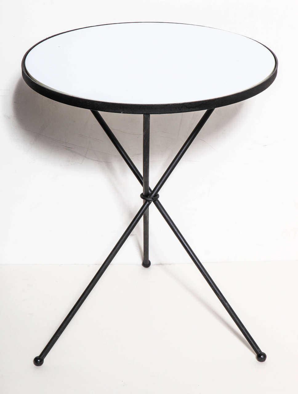 Mid Century California Modern White Vitrolite and Black Wrought Iron Tripod Table.  Featuring a Black ring center, ball feet, a round durable White Vitrolite Top encircled within a rimmed Black painted Wrought Iron frame.  Versatile, Indoor Outdoor