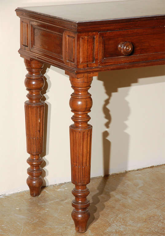 Tall, stately, hand-carved, walnut console table with large center drawer. Original marble top. The whole on turned and fluted legs.