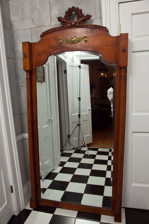 We love this architecturally-commanding and very unusual hand-carved dressing mirror with original brass ormolu mounts and the original beveled mirror. A stunning carved laurel wreath with crossed torchieres crowns the top and elegant reeded columns