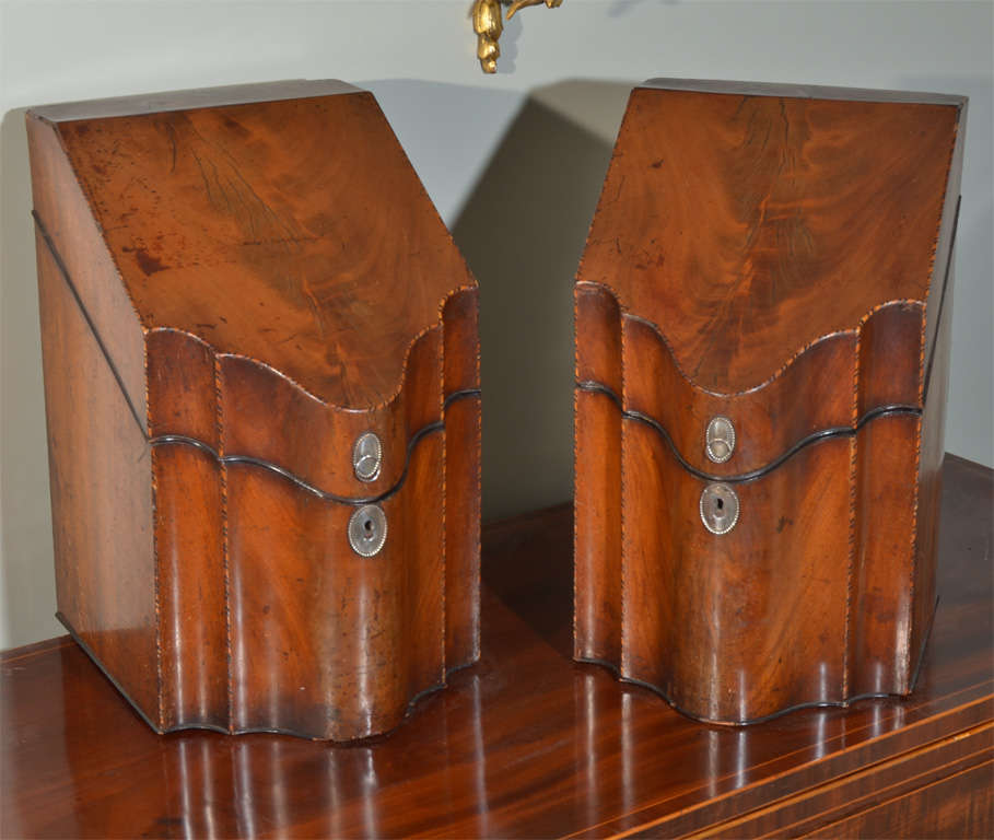 Pair of mahogany fitted Knife Boxes from England, early 19th century. Serpentine front with chequered inlay on edges and lids, interiors fitted with cutlery inserts- with line edge inlay, oval silver metal escutcheons & backplates for ring pulls.