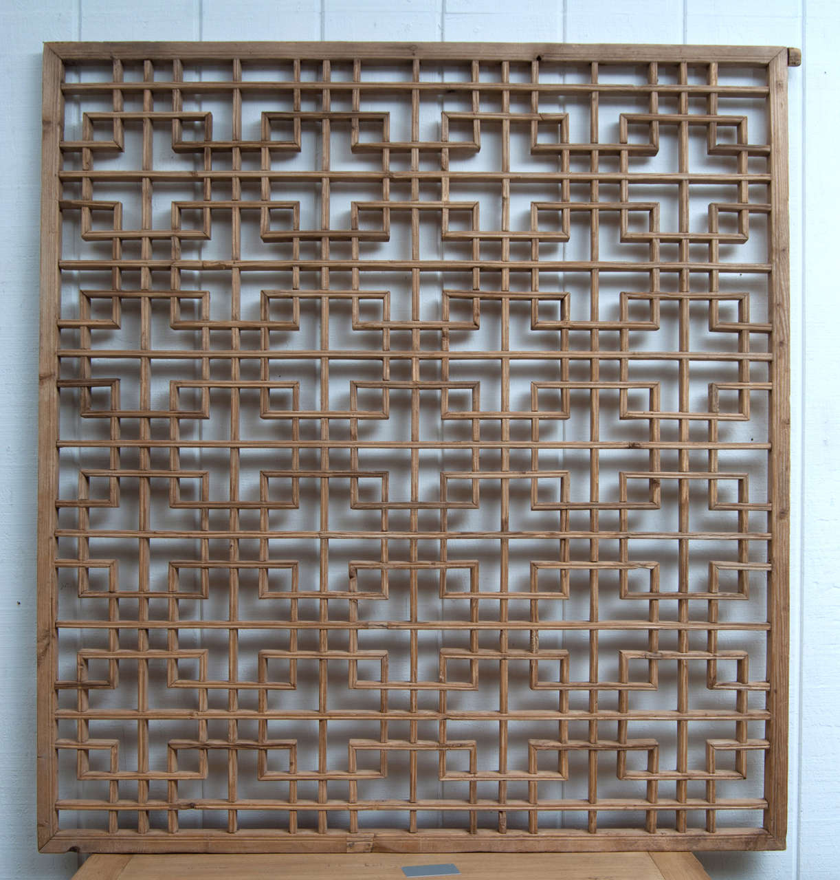 Chinese lattice window panel of minimal geometric design. Pale, raw softwood.