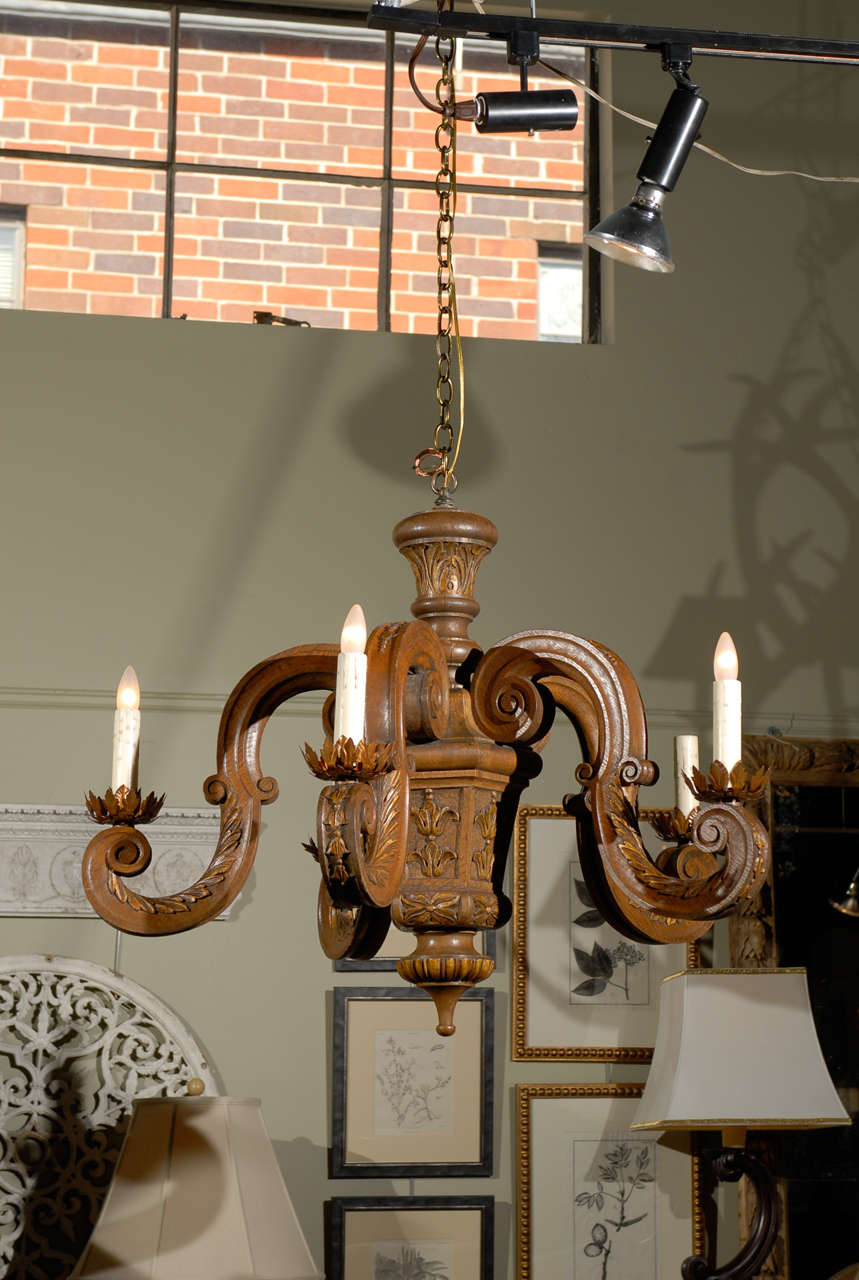 French carved oak five-light chandelier with s-scroll arms and gilded accents from the 19th century. This French wooden chandelier features a central polygonal column with floral motifs, supporting five s-scroll arms adorned with acanthus leaves.