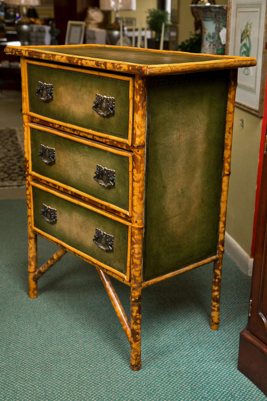 Bamboo trimmed furniture became popular in France and England in 1880.  They brought the bamboo from the Caribbean and made the furniture in Manchester, England. This unique three drawer commode is completely hand made. Green leather top, sides and