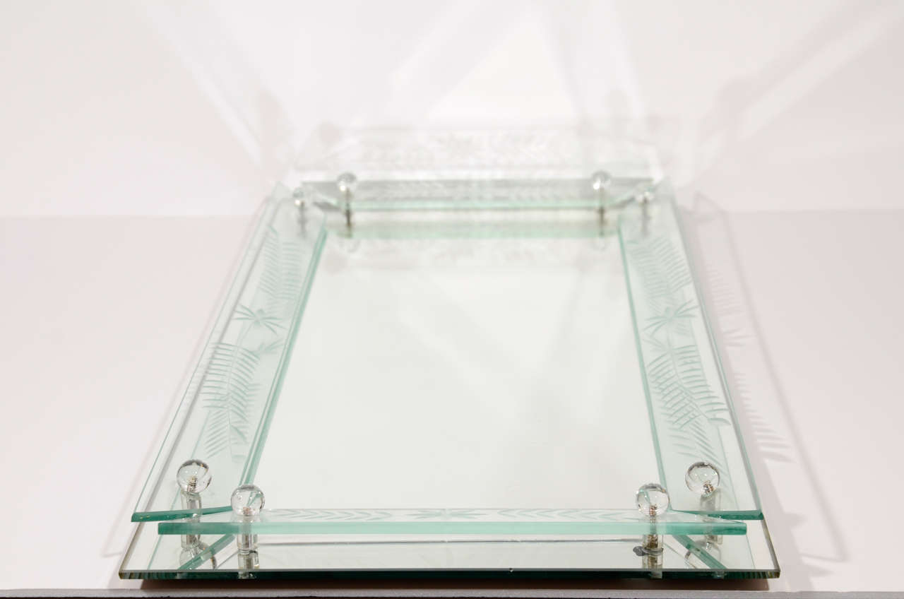 Elegant mirrored vanity tray or serving tray with raised beveled glass borders. The glass borders have reverse etched laurel leaf designs as well as glass ball finials. Perfect for dressing area or powder room, or as a barware tray.