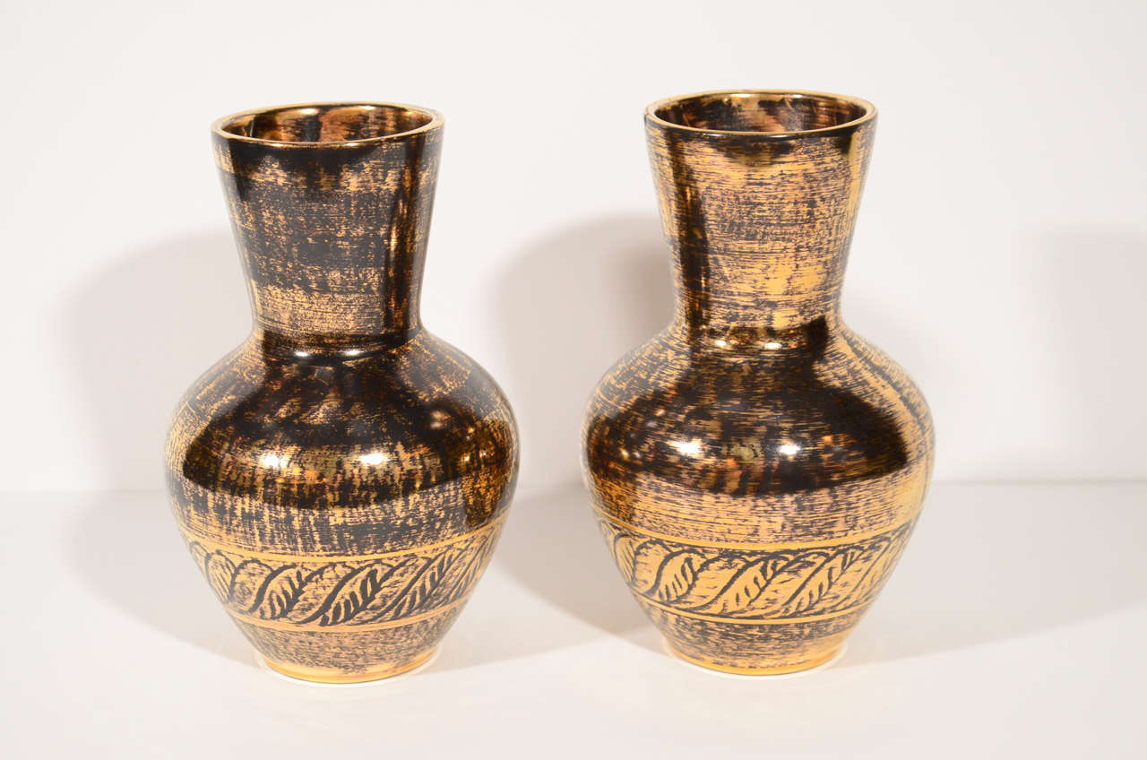 Pair of elegant ceramic vases in blackened gold leaf finish and with modern urn design.  The vases have laurel leaf banded details and are signed Stangl.