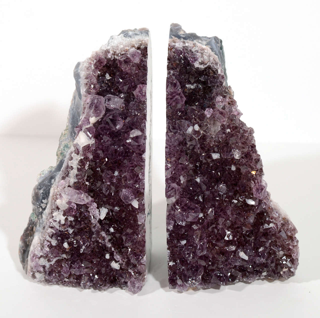 Pair of exquisite amethyst crystal bookends with rough crystaline quartz in hues of violet to deep purple. The bookends have rough and polished geode centers with unusual coloration in hues of variant hunter green and with grey agate banding. These