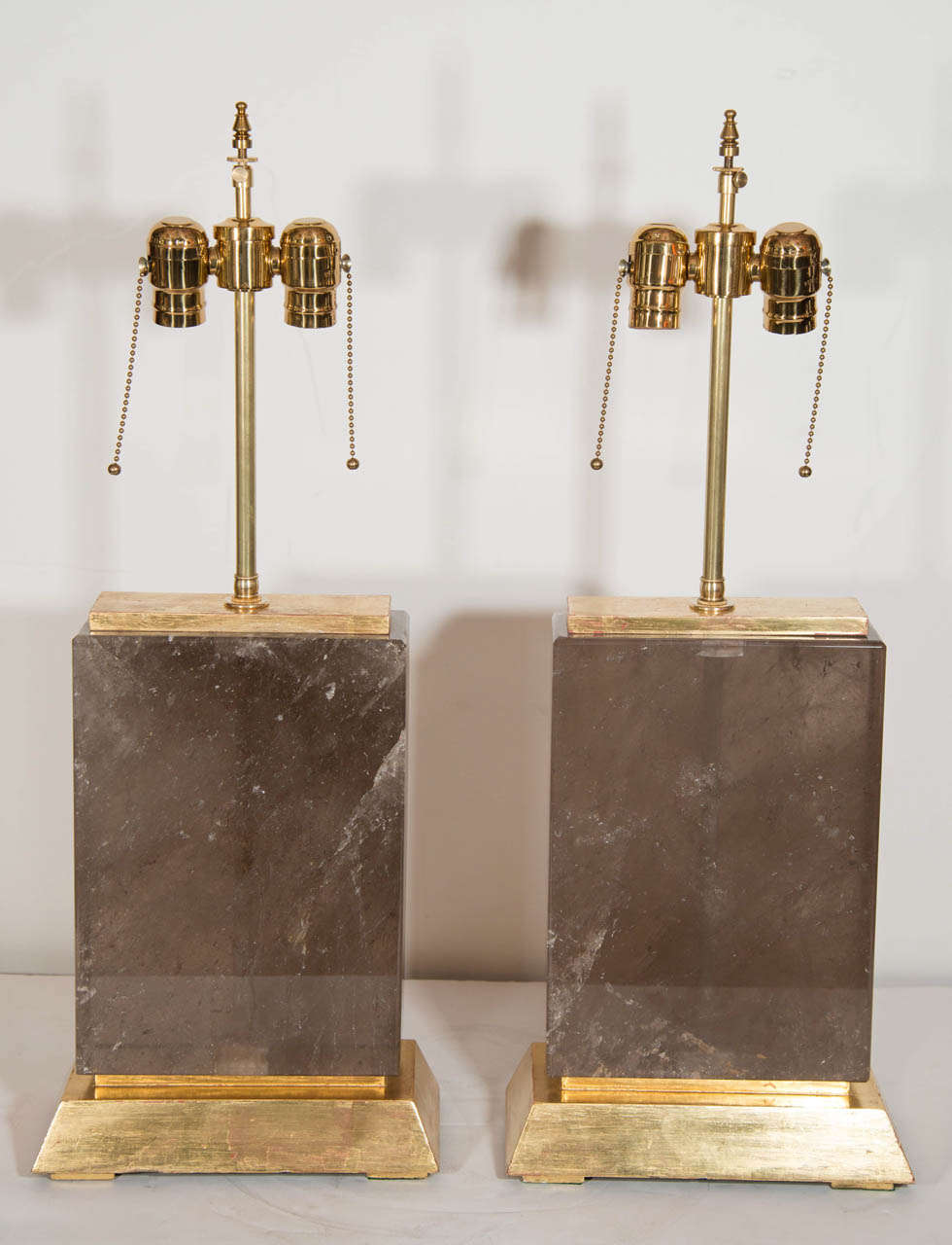 A pair of unique and large Art Deco style gilt mounted cut smokey rock crystal book form lamps.