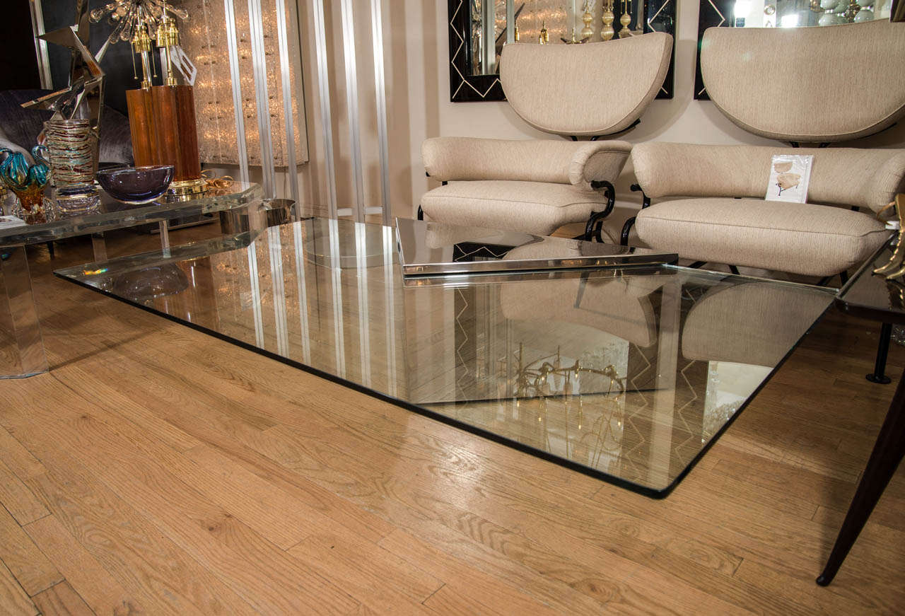 Rectangular cantilevered glass coffee table with triangular stainless steel base by Brueton.