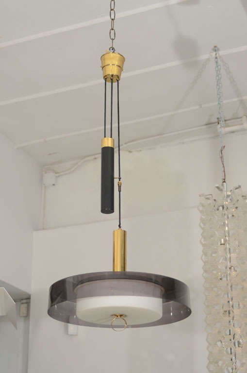 Chic weighted adjustable pulley ceiling light. An acrylic grey shade frames a white glass centre light. A golden ring allows for easy height adjustment.