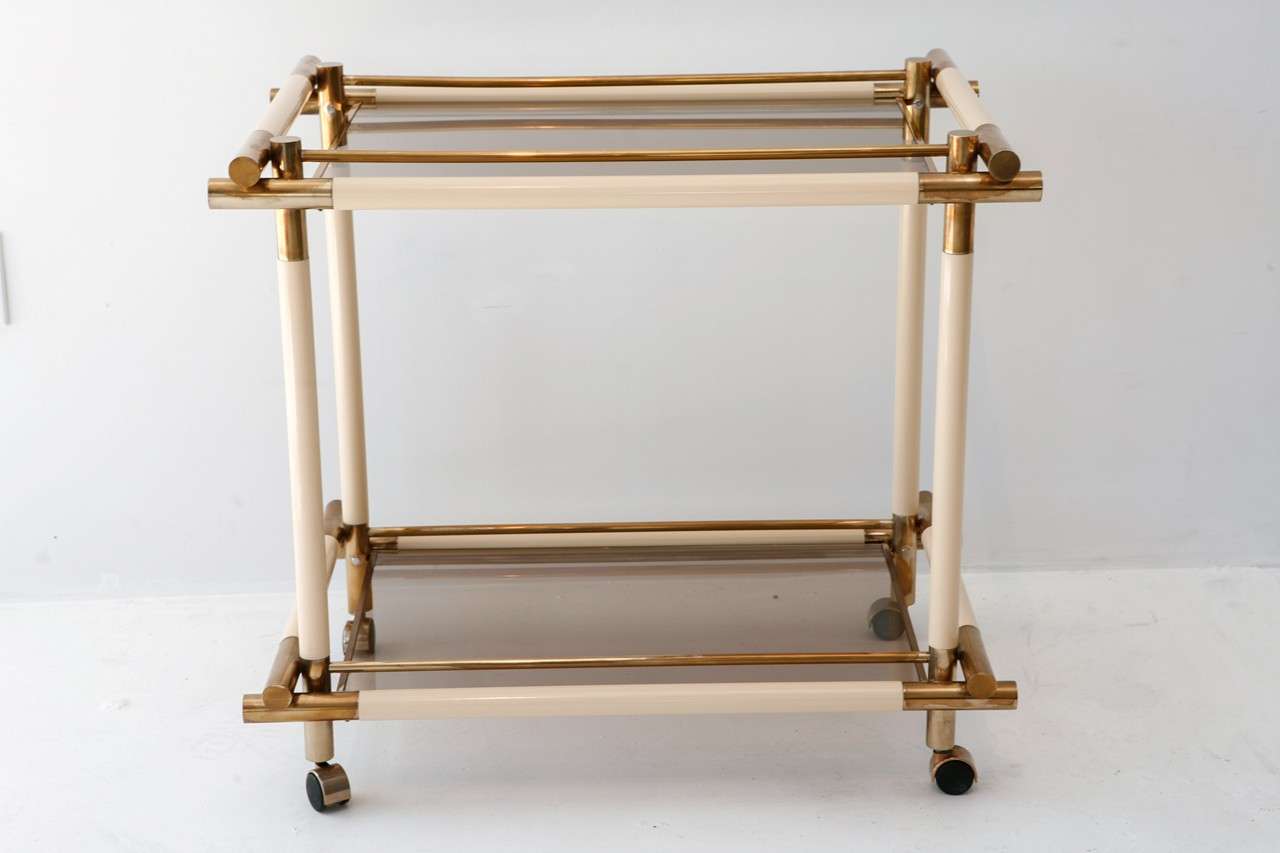 A chic Italian brass, acrylic & smoked tempered glass bar cart on four casters.
