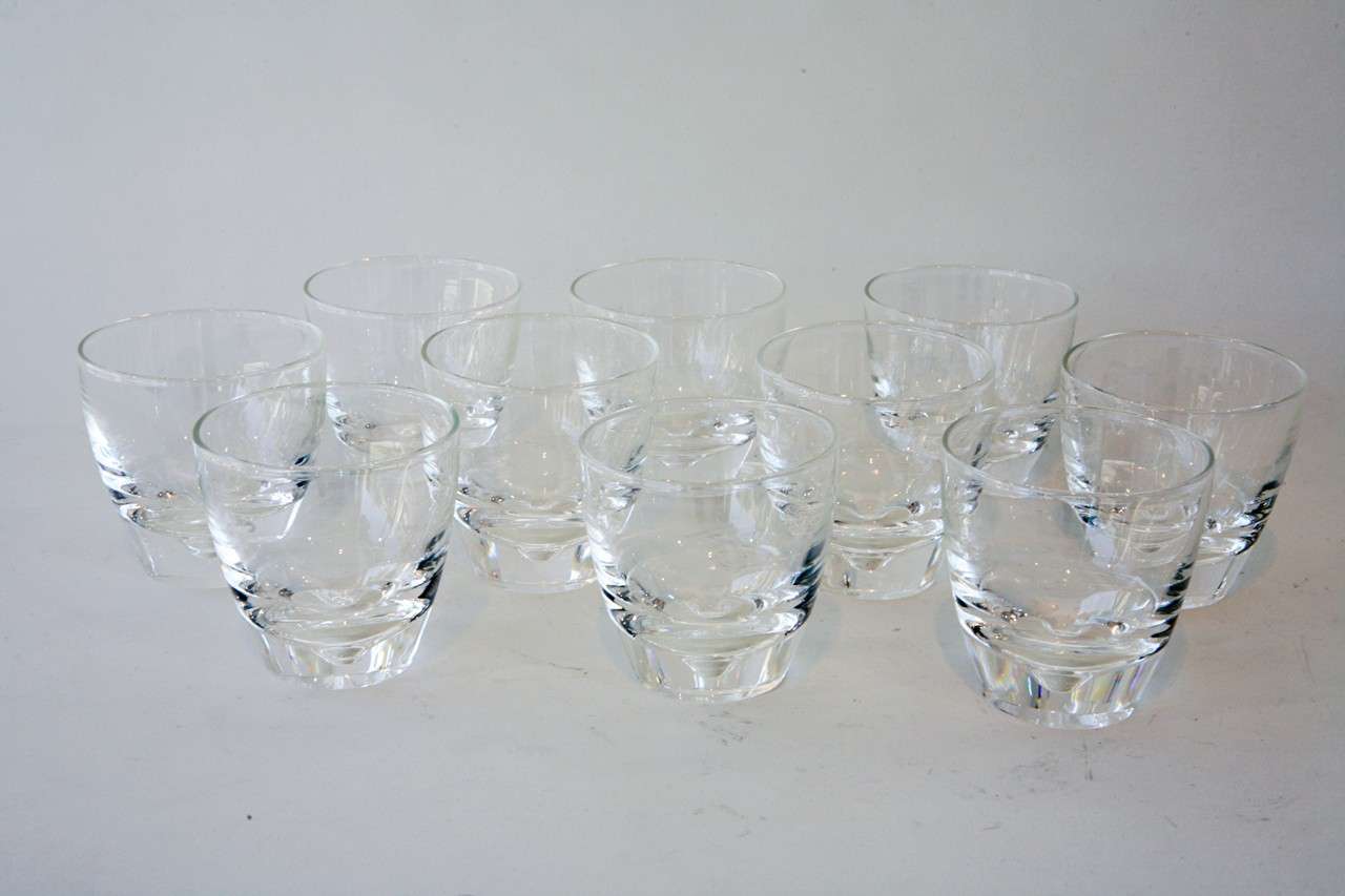 A beautiful set of ten crystal old fashioned glasses with a dimple detail in the base by Steuben Glass. This glass was designed by artist George Thompson in 1947. All of the glasses are etched with the Stueben signature on the bottom (see last