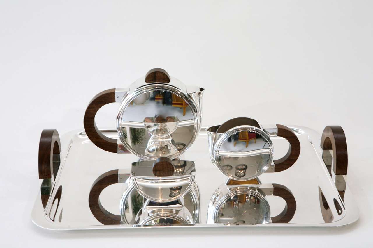 Christofle's silver plate 1925 tea service, designed in the early 20th century, is quintessential Art Deco. This tea service is comprised of a tea pot, creamer, lidded sugar and tray, all with walnut handles and knobs. Measurements given below are